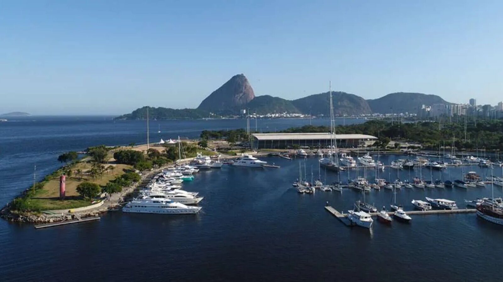 Vista aérea da Marina da Glória com lanchas e veleiros atracados e o Pão de Açúcar ao fundo